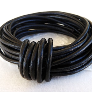 Può includere: Un braccialetto in cordoncino di cuoio nero con un design annodato. Il cordoncino è avvolto su se stesso per creare un braccialetto spesso e testurizzato.