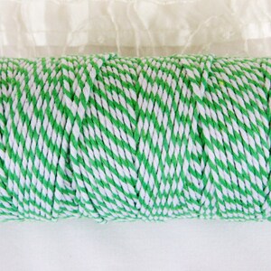 May include: A spool of green and white striped twine. The twine is twisted and has a natural texture.