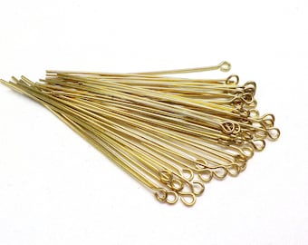 May include: A bunch of gold-colored head pins with a loop at the end. The pins are arranged in a fan shape.