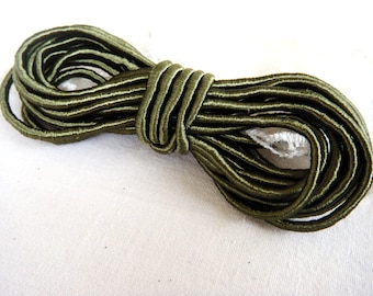 May include: A spool of olive green elastic cord. The cord is tightly wound and ready to be used for sewing or crafting projects.