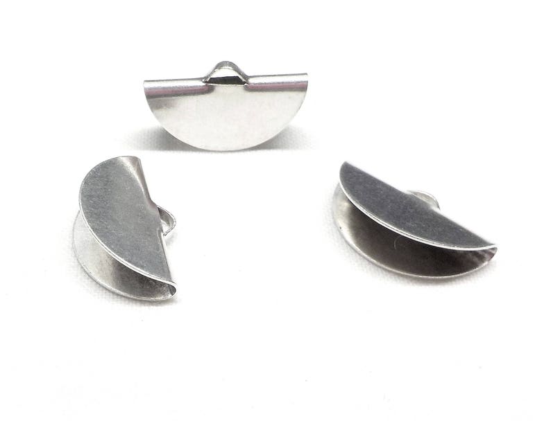 Op de afbeelding: Drie zilveren metalen halfronde kralencaps. De caps zijn aan &eacute;&eacute;n kant open en hebben een kleine lus aan de bovenkant.