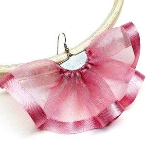 Op de afbeelding: Oorbellen van roze tule en satijn met een zilveren metalen bevestiging. De oorbellen hebben de vorm van een waaier en hebben een delicate, vrouwelijke uitstraling.