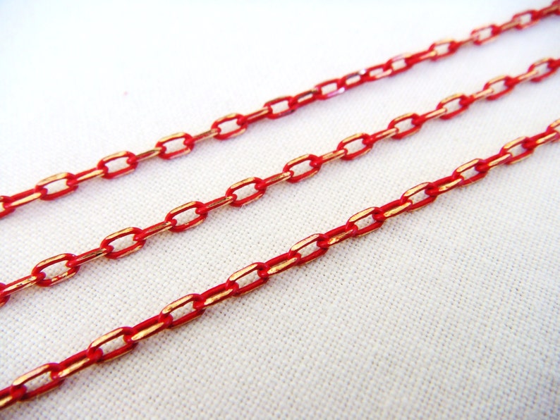 K&ouml;nnte beinhalten: Drei Str&auml;nge rote Kette mit goldener Akzent. Die Kette ist aus Metall und hat eine polierte Oberfl&auml;che.