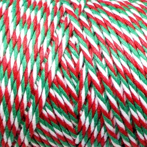 May include: Red, white, and green twine with a striped pattern. The twine is wound into a ball.