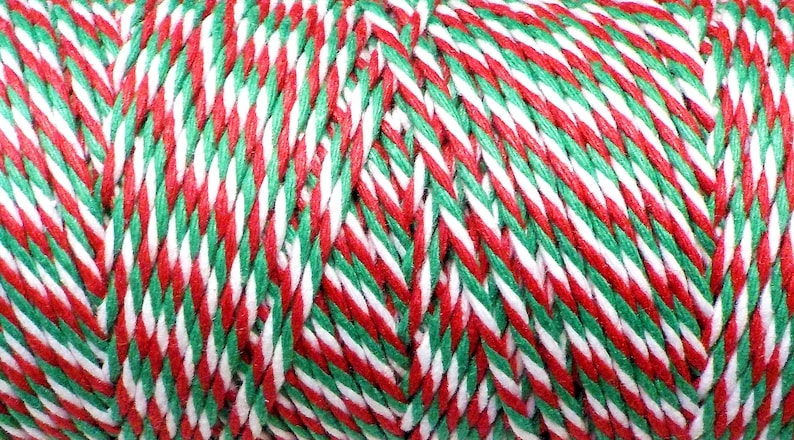 May include: Red, white, and green twine with a striped pattern. The twine is wound into a ball.
