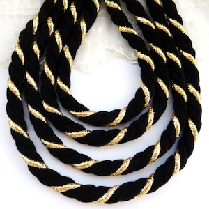 May include: Black and gold rope trim with a twisted design. The rope is thick and has a shiny gold thread woven into it.