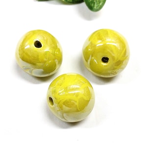 Könnte beinhalten: Drei gelbe Keramikperlen mit einem Wirbelmuster und einem Loch in der Mitte.