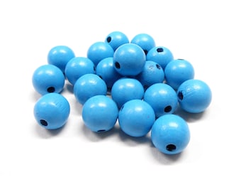 May include: A pile of light blue wooden beads with a hole in the center of each bead.