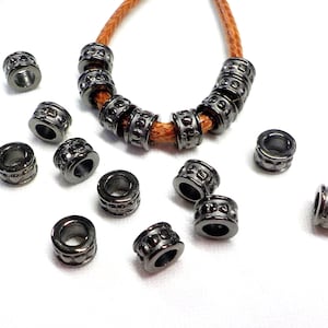 May include: A set of black metal beads with a decorative pattern. The beads are strung on a brown leather cord. The beads are approximately 1/2 inch in diameter.