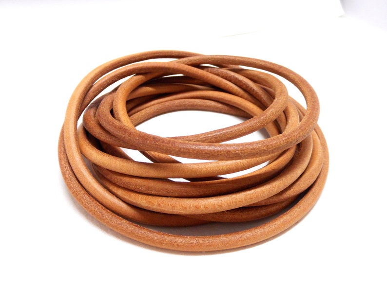 May include: A close-up of a coil of light brown leather cord. The cord is smooth and supple, and it is perfect for crafting projects.