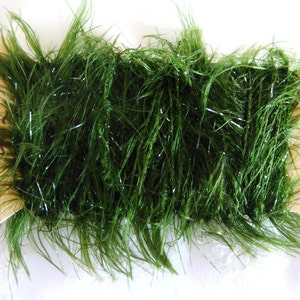 May include: A spool of green tinsel with a silver shimmer. The tinsel is wrapped around a cardboard spool.