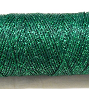 Può includere: Un rocchetto di filo metallico verde. Il filo è avvolto stretto e ha una finitura lucida e scintillante.