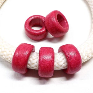 以下が含まれることがあります： 中央に穴の開いた赤い木製のビーズが3つ。ビーズは白いロープに通されています。