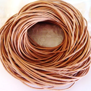 Puede incluir: Primer plano de una bobina de cordón de cuero marrón claro. El cordón tiene un diámetro de aproximadamente 3 mm y es perfecto para la elaboración de joyas, pulseras y otros proyectos de cuero.