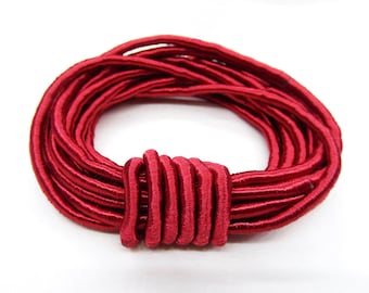 May include: A spool of red elastic cord, wound into a circle with a knot in the center.
