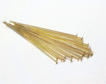 May include: A bunch of gold-coloured head pins with flat heads. The pins are arranged in a fan shape.