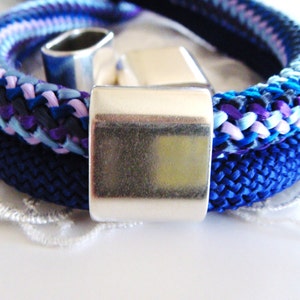 May include: A blue and purple braided rope bracelet with a silver metal clasp.