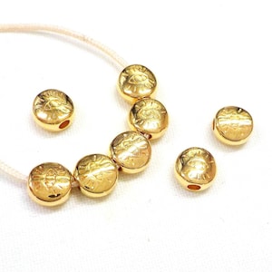 Puede incluir: Cuentas doradas con un diseño de ojo. Las cuentas tienen un agujero en el centro para enhebrar.