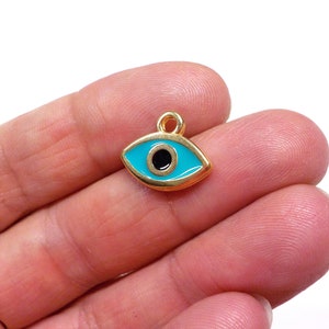 May include: Gold-tone charm with a blue evil eye design. The charm has a black pupil and a gold loop for attaching to a necklace or bracelet.