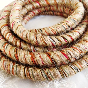May include: A thick, braided rope made of natural fibers with a multi-colored pattern. The rope is woven with beige, brown, orange, red, and green threads.