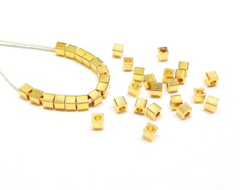 May include: A gold necklace with square beads, and a pile of loose gold square beads.