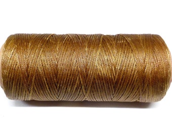 May include: A spool of golden-brown waxed thread, tightly wound and ready for use. The thread has a slight sheen, suggesting a smooth texture. Ideal for crafting, sewing, or jewelry making.