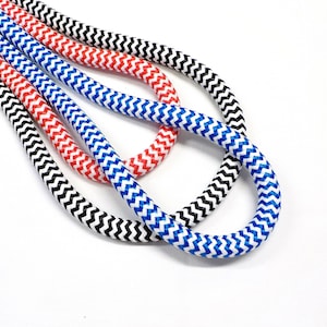 May include: Three cords of rope with a zig-zag pattern. The cords are black and white, red and white, and blue and white.