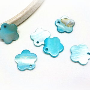 May include: Six turquoise blue flower-shaped charms with a hole in the center. The charms are made of iridescent mother of pearl.