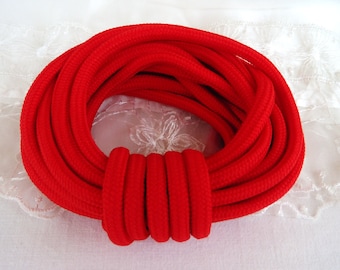 May include: A coil of bright red cord, tightly wound into a circle. The cord is thick and textured, with a soft, fuzzy appearance.