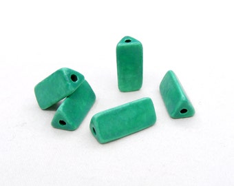 May include: Five teal green ceramic triangle beads with a hole through the center. The beads are all different sizes and shapes.