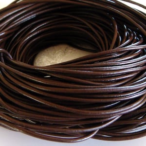 Può includere: Primo piano di un rotolo di cordoncino in pelle marrone. Il cordoncino è avvolto strettamente ed è pronto per essere utilizzato per progetti di artigianato.
