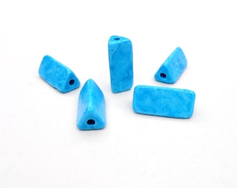May include: Five turquoise blue ceramic beads with a hole in the center. The beads are in the shape of a rectangle and a triangle.