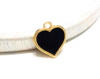 Puede incluir: Encanto de corazón dorado con un centro de esmalte negro. El encanto tiene un bucle en la parte superior para sujetarlo a un collar o pulsera.