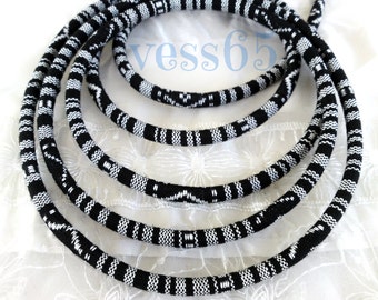 May include: A collection of black and white patterned rope necklaces. The ropes are arranged in a circular pattern, showcasing a repeating geometric design. The necklaces are made of a thick, durable material, suitable for various uses.