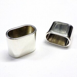 May include: Two silver oval napkin rings. The rings are smooth and shiny.