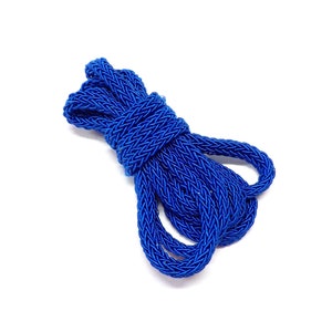 Può includere: Un primo piano di un cordoncino intrecciato blu, attorcigliato e arrotolato in una forma compatta. Il cordoncino è fatto di un materiale morbido e flessibile e ha una texture liscia e uniforme.