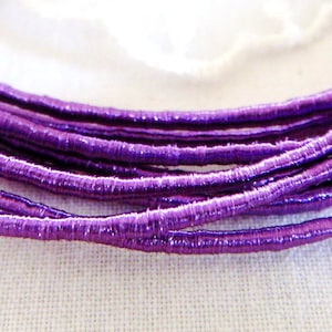 May include: A close-up of a bundle of purple metallic cord. The cord is thin and has a slightly textured surface.