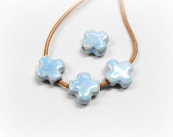 May include: A light blue ceramic necklace with four cross-shaped beads. The necklace is made of brown leather cord.