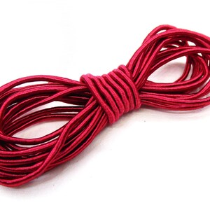 May include: A spool of red elastic cord. The cord is tightly wound and has a shiny finish.