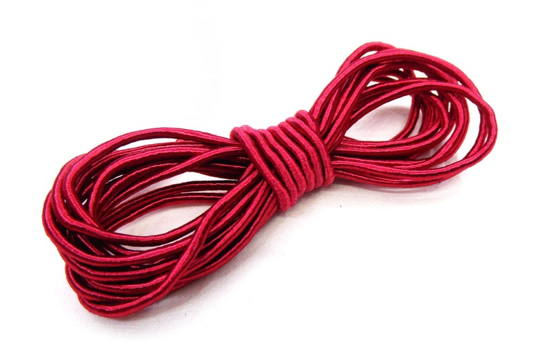 May include: A spool of red elastic cord. The cord is tightly wound and has a shiny finish.