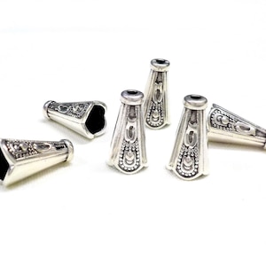 Puede incluir: Seis tapas de cuentas de metal de color plateado en forma de cono con un diseño ornamentado. Las tapas tienen un acabado liso y brillante y son perfectas para agregar un toque de elegancia a los proyectos de joyería.
