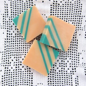 May include: Three bars of soap with a peach and teal color scheme. The soap bars have a striped pattern.