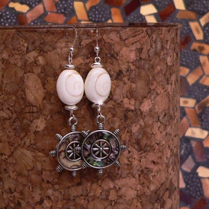 May include: A pair of silver earrings with white shell beads and abalone shell wheel charms.