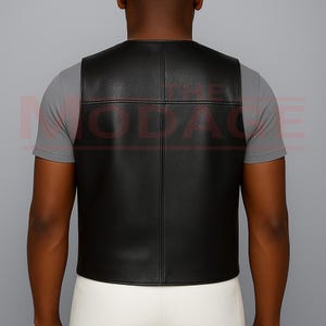 Puede incluir: Un chaleco de cuero negro con un dise&ntilde;o de patr&oacute;n cuadrado. El chaleco es sin mangas y tiene un cuello redondo. La parte trasera del chaleco es visible y parece estar hecha de un material liso y brillante. El chaleco se lleva sobre una camiseta gris.