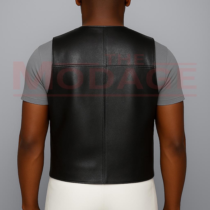 Puede incluir: Un chaleco de cuero negro con un dise&ntilde;o de patr&oacute;n cuadrado. El chaleco es sin mangas y tiene un cuello redondo. La parte trasera del chaleco es visible y parece estar hecha de un material liso y brillante. El chaleco se lleva sobre una camiseta gris.