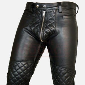 Könnte beinhalten: Schwarze Lederhose mit einem gesteppten Rautenmuster auf der Vorderseite und den Knien. Die Hose hat einen silbernen Reißverschluss und Knopfverschluss, Gürtelschlaufen und Taschen.