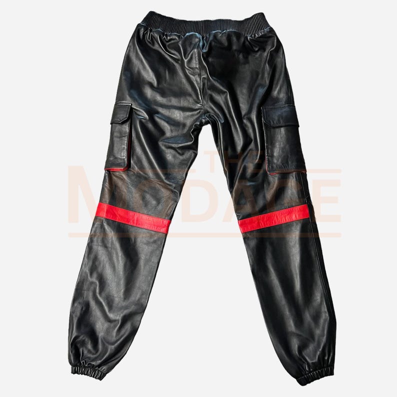 K&ouml;nnte beinhalten: Schwarze Leder-Cargohose mit roten Streifen an den Seiten. Die Hose hat einen Kordelzugbund und zwei gro&szlig;e Cargotaschen an den Seiten.