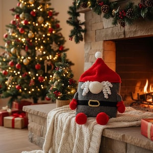Puede incluir: Escena navideña con un árbol decorado, una chimenea encendida y un peluche con forma de gnomo. Los regalos se colocan cerca de la chimenea y del árbol. El gnomo tiene un gorro rojo y pies rojos.