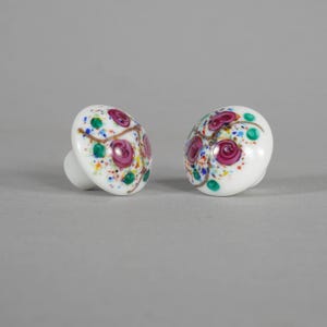 Könnte beinhalten: Eine weiße Keramik-Tasse mit schwarzem Henkel und dem Text "But First, Coffee" in schwarzer, handschriftlicher Schrift. Die Tasse steht auf einer weißen Oberfläche.