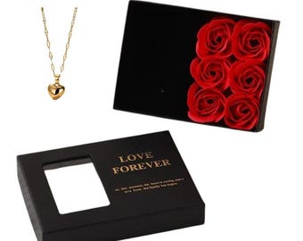 May include: A black gift box with a gold inscription that reads "Love Forever" and a clear window to view the contents. The box contains a gold heart necklace and a box of red roses.
